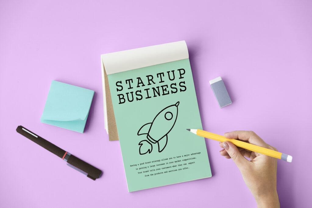 Startup planning workspace with notebook titled “Startup Business,” rocket icon, and office supplies – symbolizing innovation and essential free tools for startups.